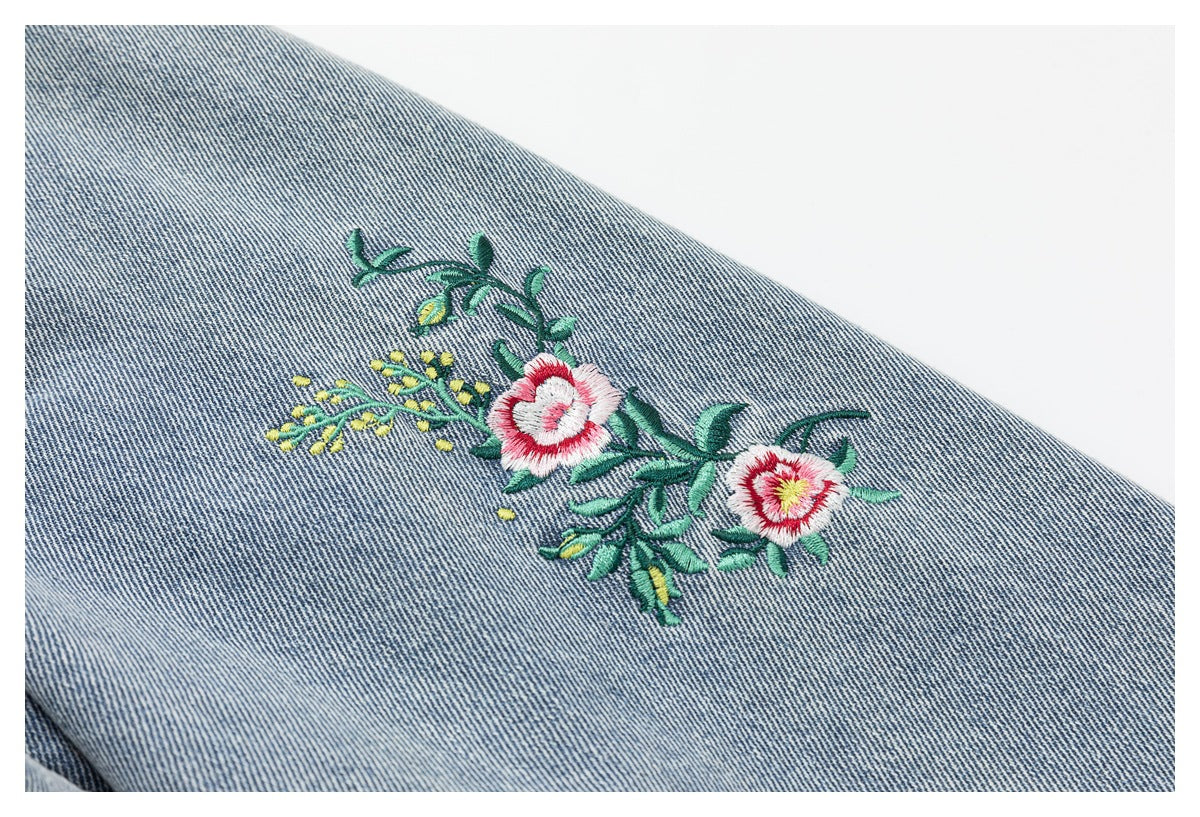 Close-up of colorful floral embroidery on blue denim.