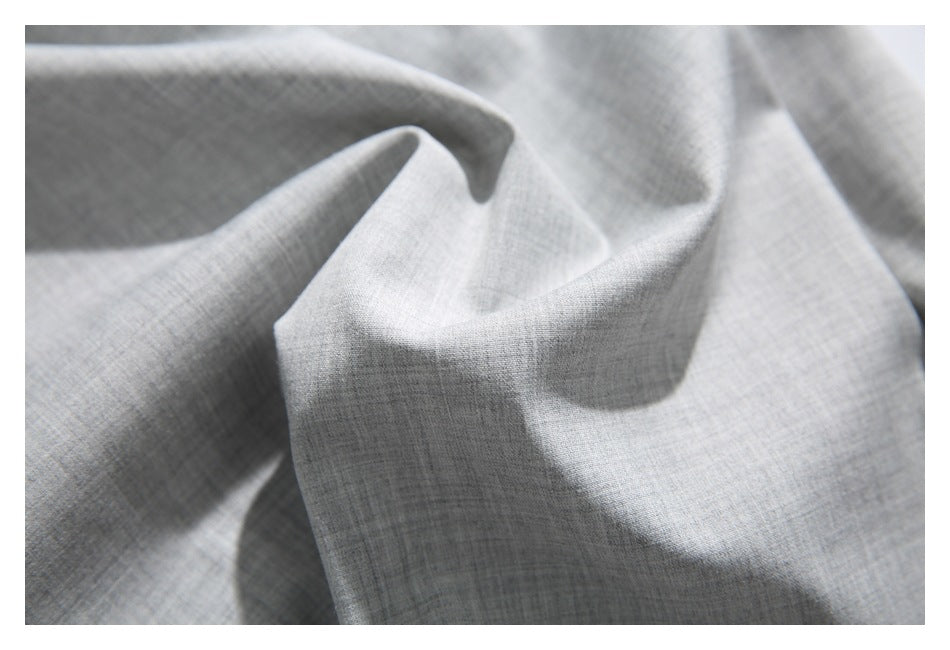 Close-up of light gray fabric gathered into soft folds, showing its subtle crosshatch texture.