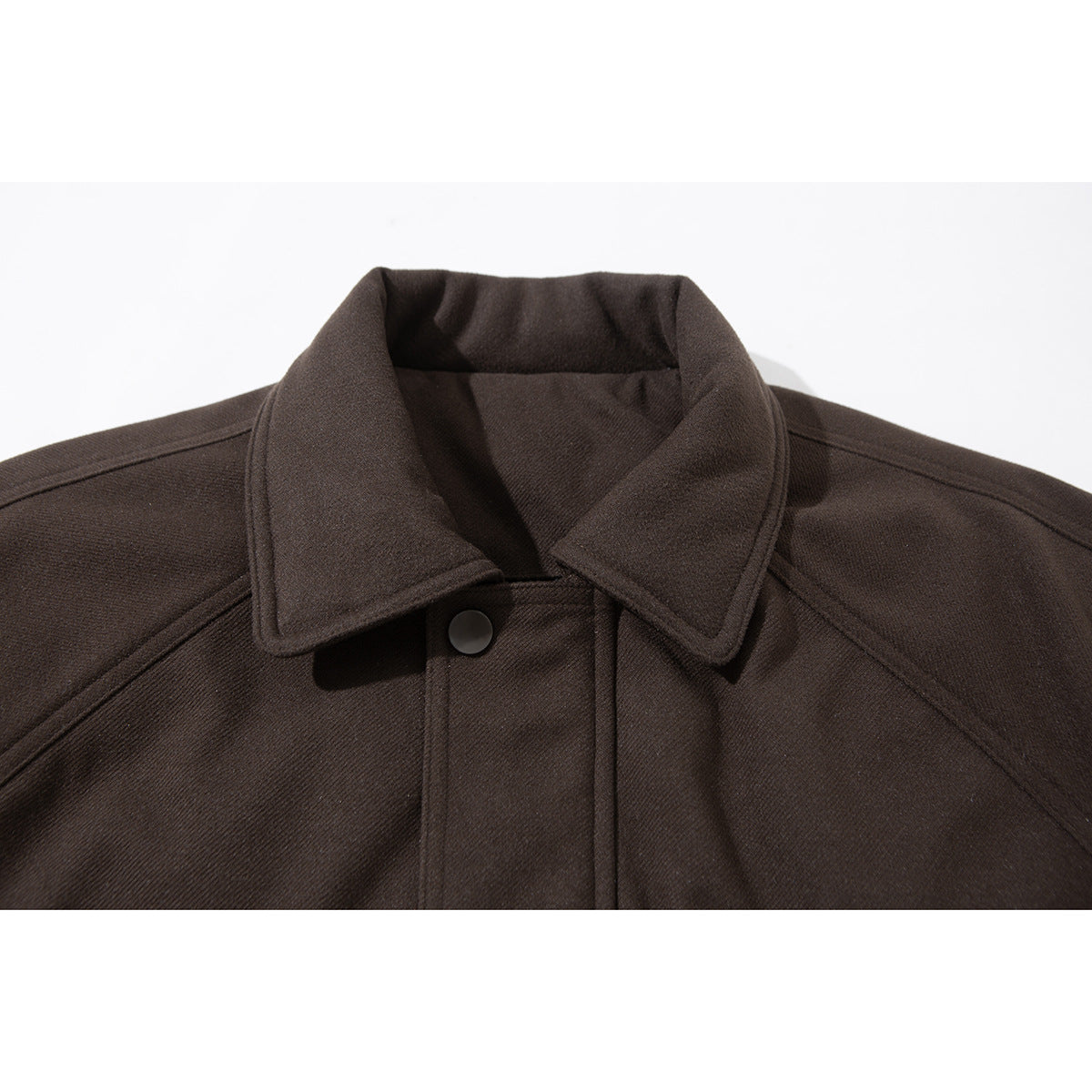 Close-up of a dark brown jacket's pointed collar, shoulder seams, and snap-button front.