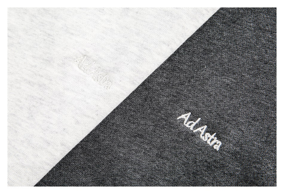 Close-up of embroidered script on light gray and charcoal sweatshirt fabric.