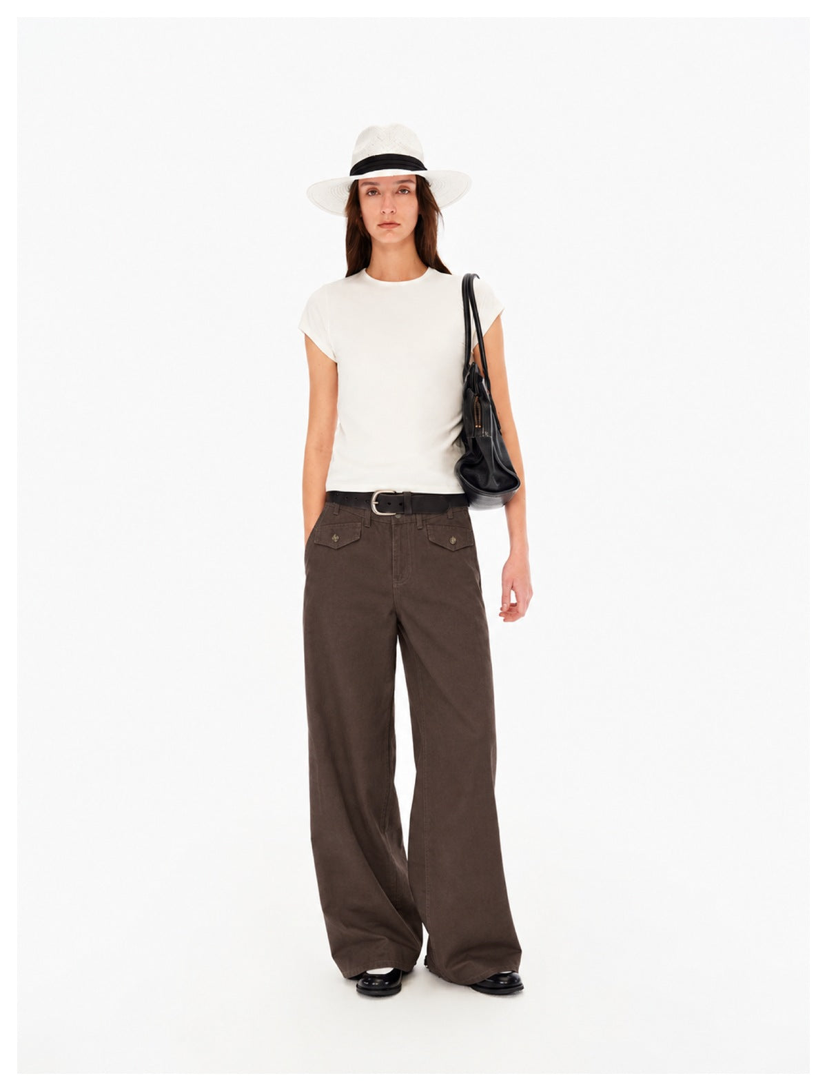 Model wearing brown wide-leg pants with front flap pockets, white tee, black belt and white hat