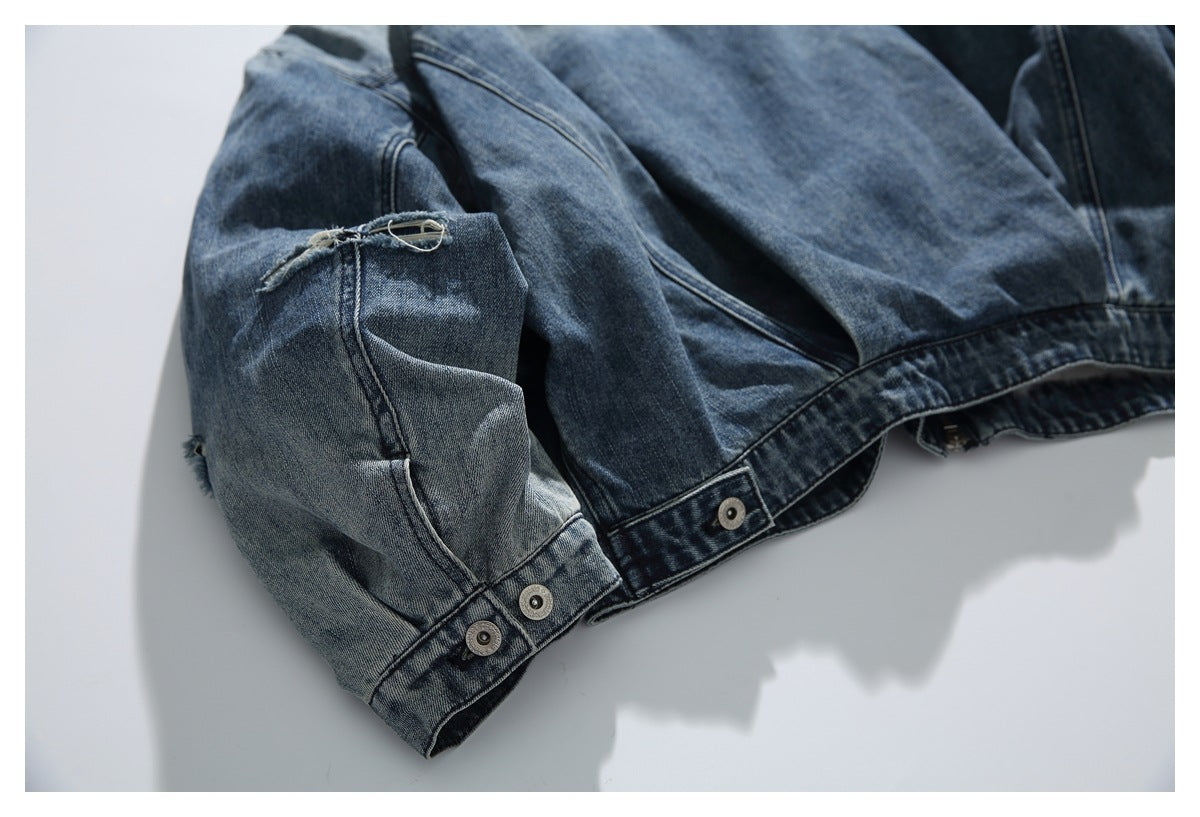 Washed denim jacket sleeve and cuff with a frayed tear and several metal snap buttons.