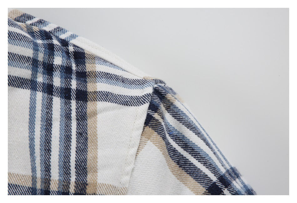 Close-up of a shoulder seam on a cream jacket patterned with navy and tan plaid.
