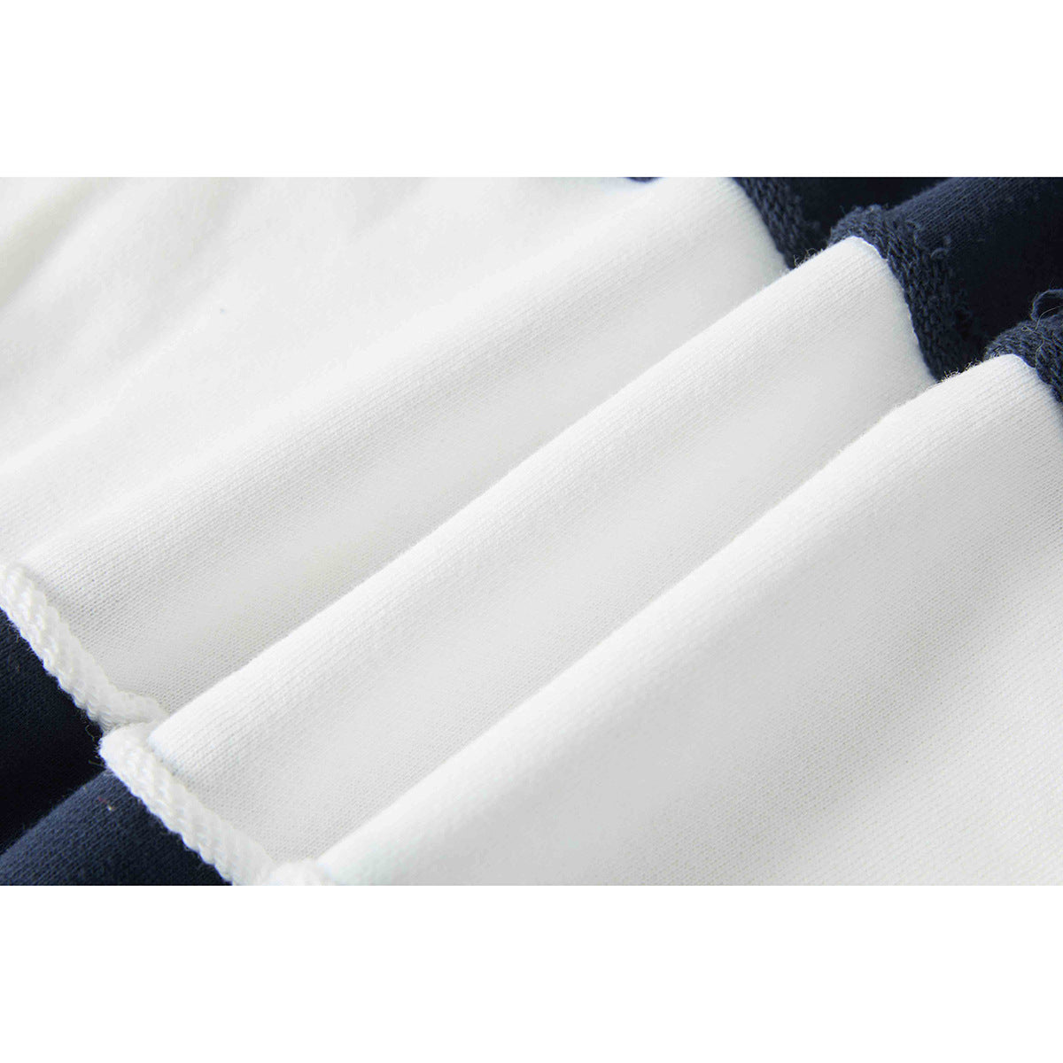 Close-up of folded white shirt fabric beside a navy section, showing the fabric surface and edge.