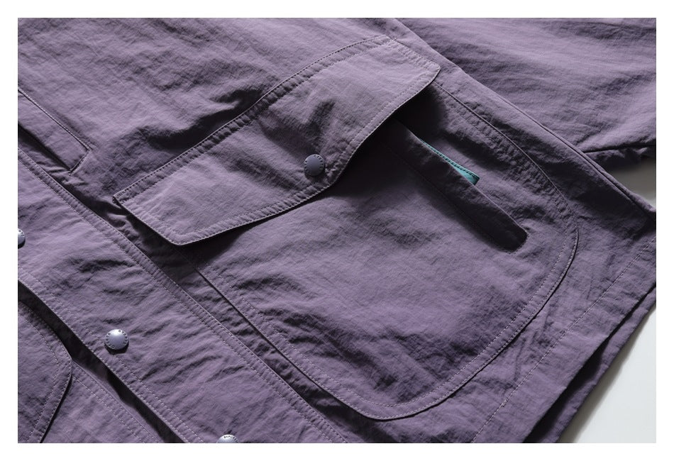 Close-up of a large flap pocket with a snap on the purple jacket, with turquoise trim visible inside.