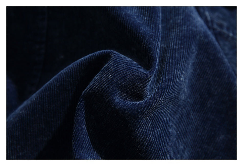 Macro view of dark navy corduroy fabric showing its fine ridged texture and folds.