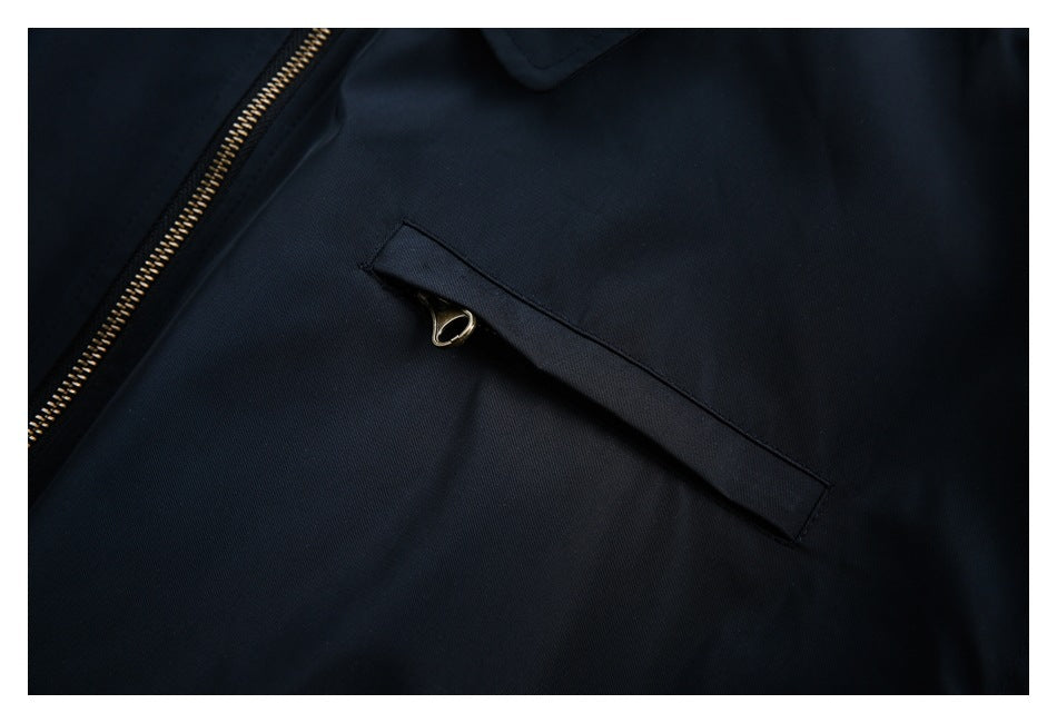 Close-up of a navy jacket's welt pocket and gold-tone zipper teeth.