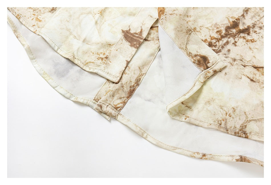 Close-up of the cream and brown printed shirt's curved hem and stitched garment edges.
