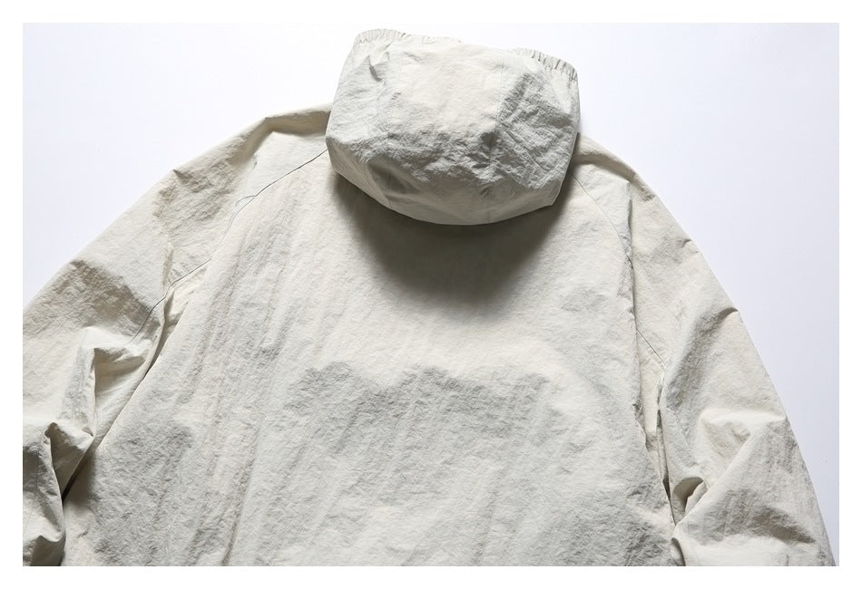 Upper back of a light beige jacket laid flat, showing its hood and long sleeves.
