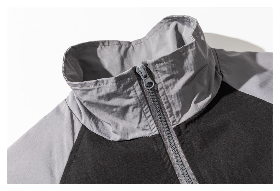 Close-up of the jacket's light gray stand collar and front zipper against black and gray panels.