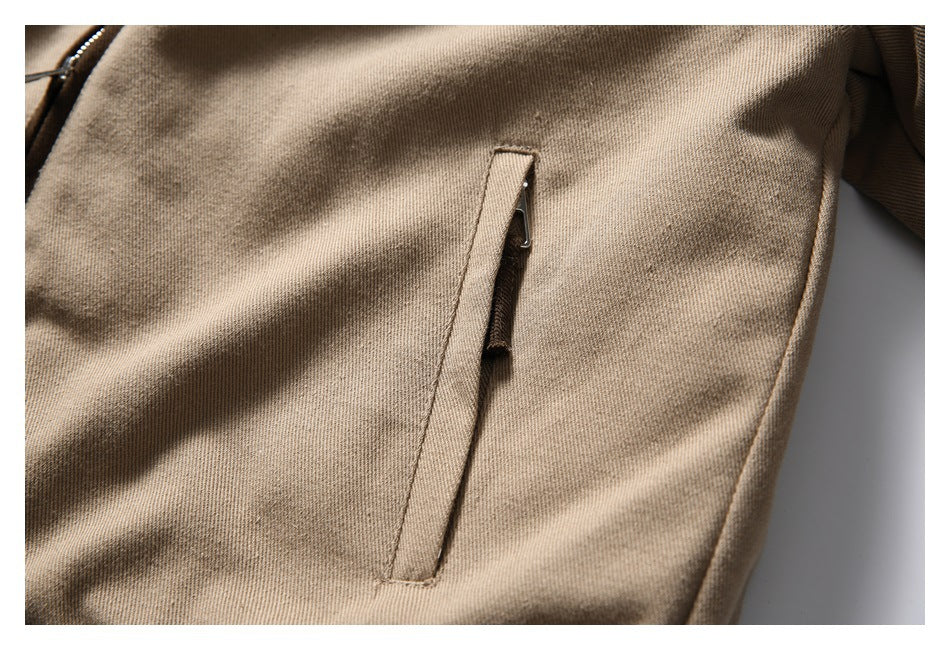 Close-up of a narrow zippered pocket on tan textured garment fabric.