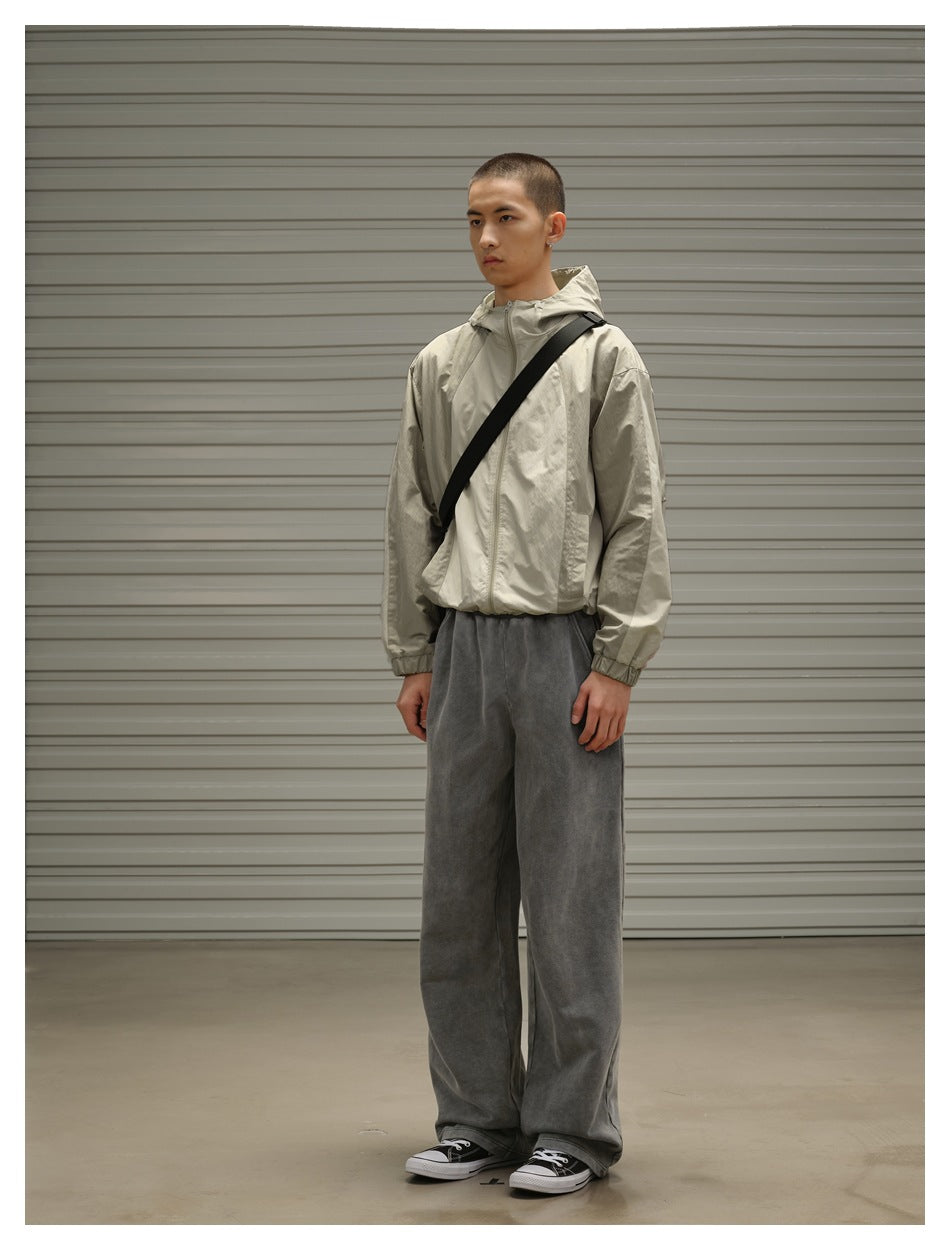 Model wearing gray washed wide-leg sweatpants with a light olive hooded jacket and black canvas sneakers, angled view