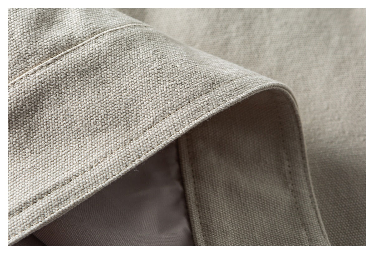 Close-up of a folded edge and stitched seam on light beige woven fabric.