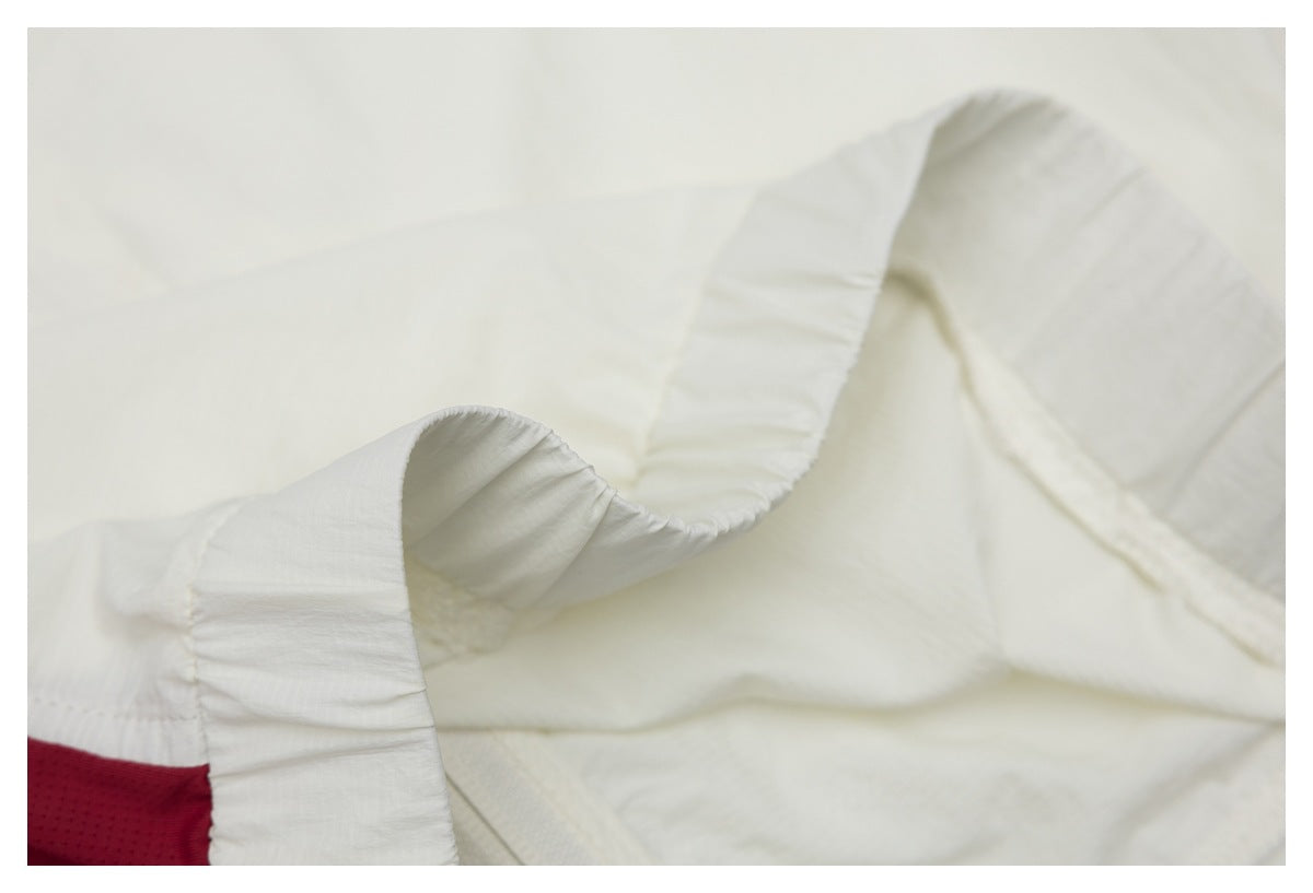 Close-up of a white gathered garment edge beside a small red mesh panel.