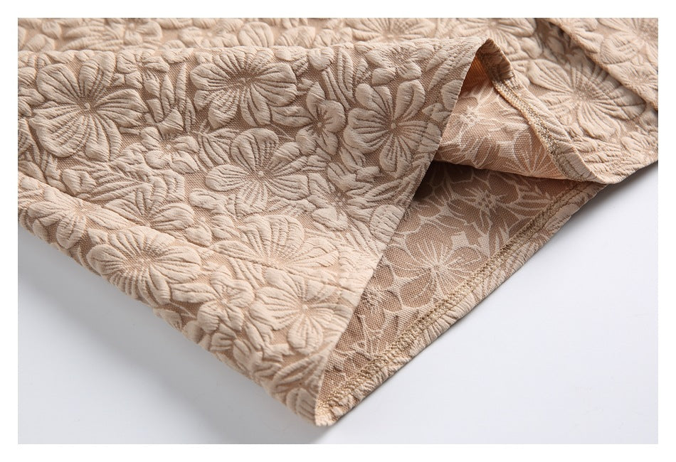 Close-up of the beige floral shirt hem, showing the stitched edge and reverse side of the fabric.