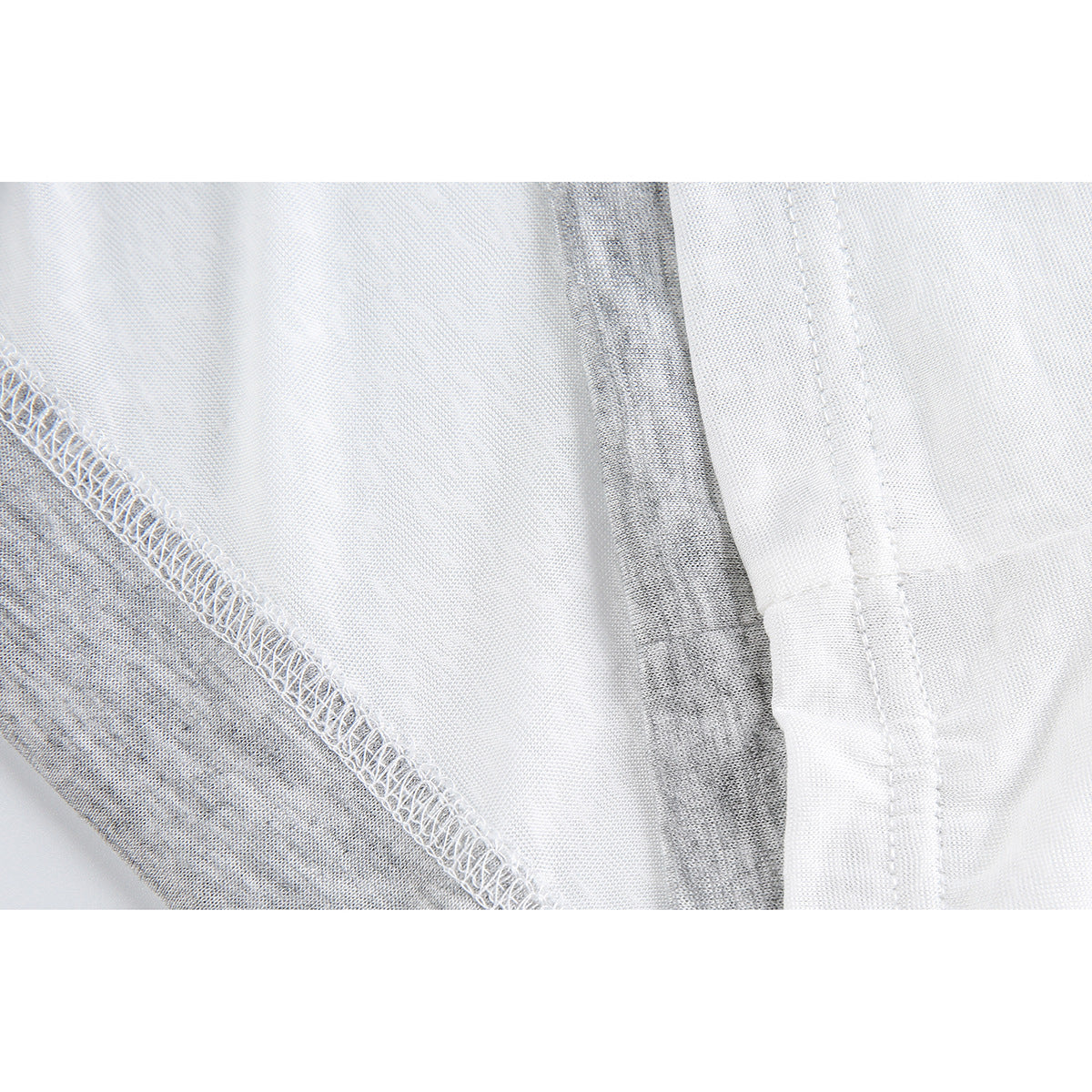 Close-up of a white top's fabric, overlocked seam, and stitched hem.