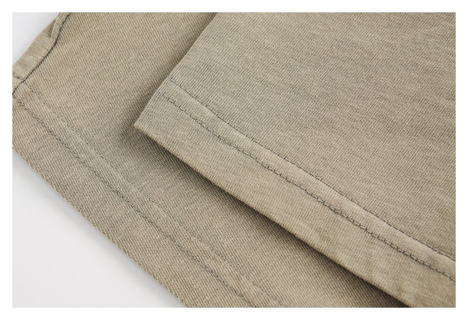 Close-up of a stitched hem on tan fabric, with another fabric edge visible beneath.