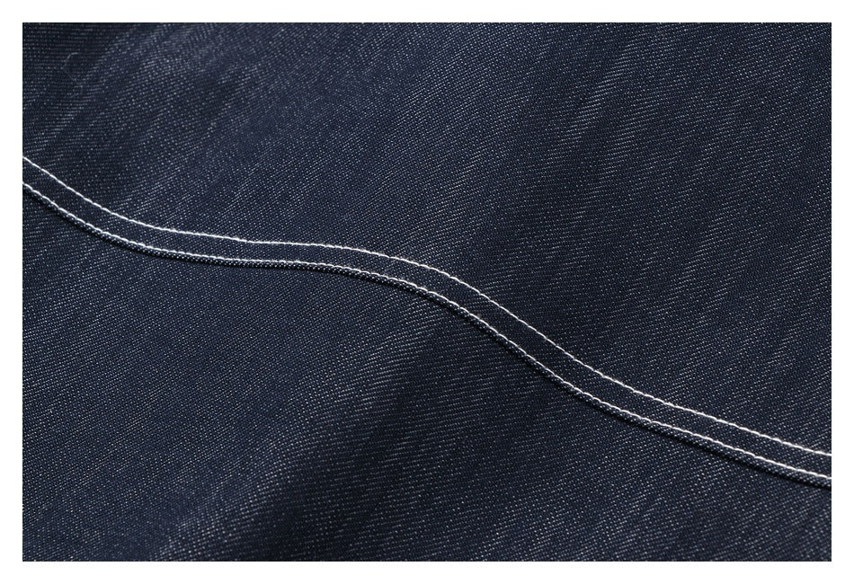Macro view of dark indigo fabric with a curved seam and parallel rows of light stitching.