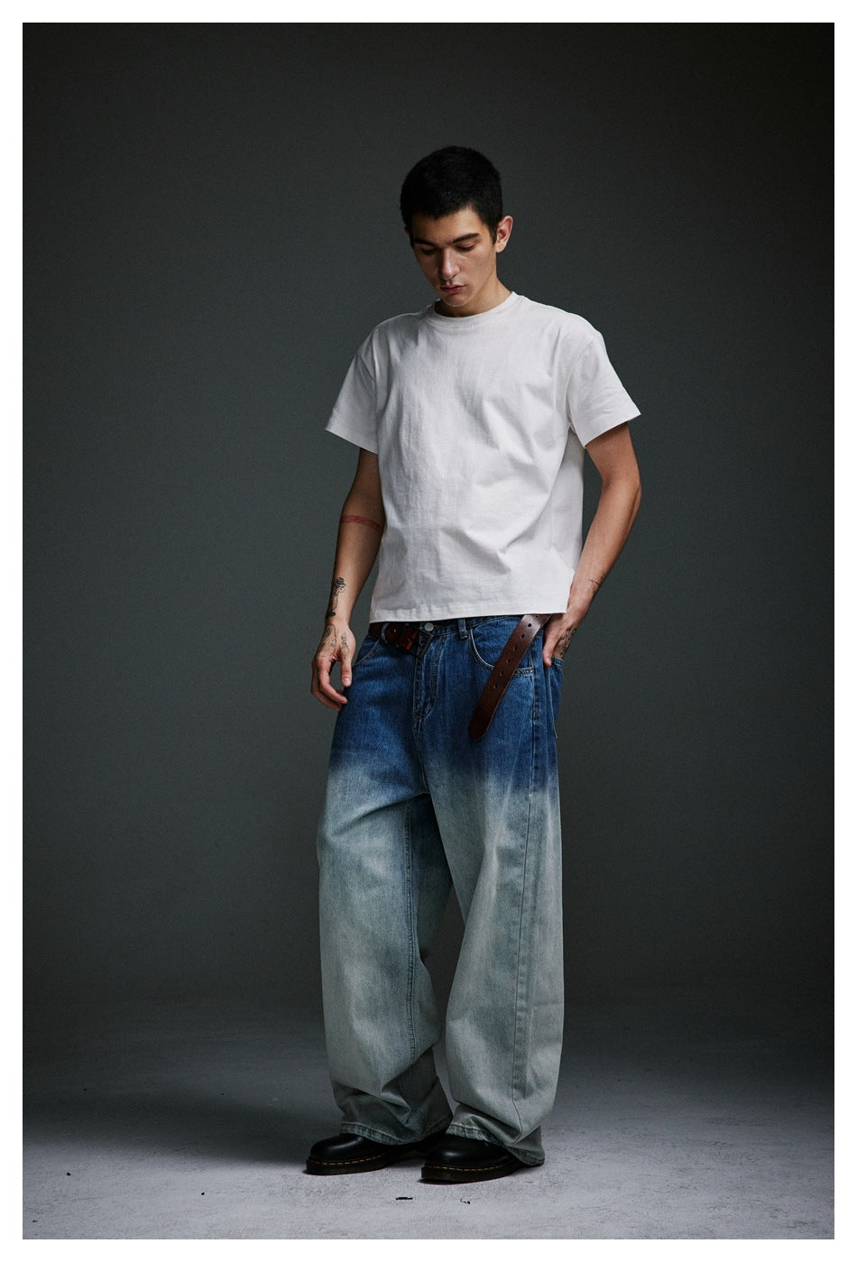 Three-quarter view of a model wearing a white T-shirt and wide blue-to-pale-wash jeans.