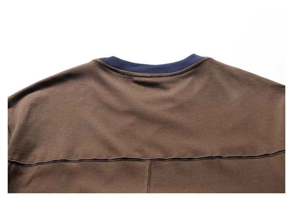 Close view of the brown T-shirt's upper back, showing the navy ribbed neckline and horizontal seam.