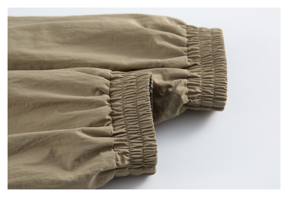 Close-up of two tan jacket sleeves with gathered elastic cuffs.