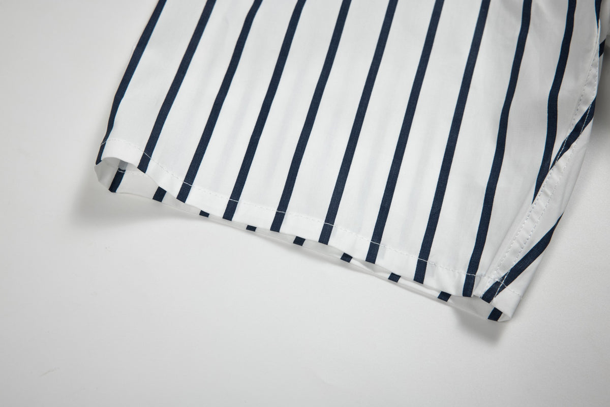 Close-up of a white shirt's side seam and hem, showing its navy vertical stripe pattern and stitching.
