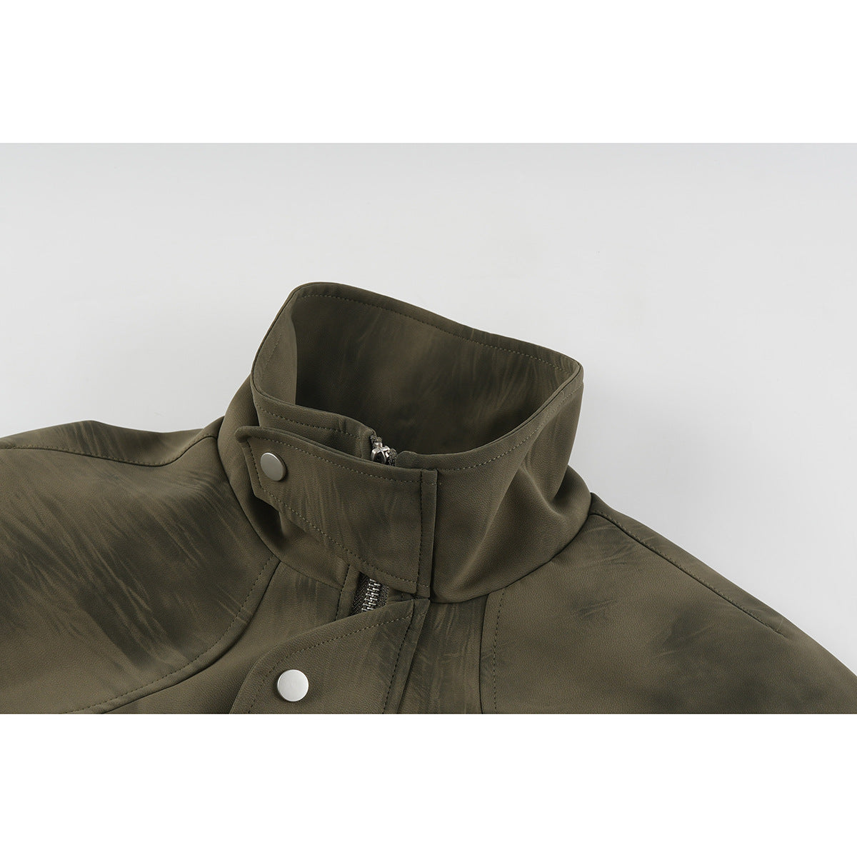 Close-up of an olive-brown jacket collar with a snap tab, zipper, and patterned surface.