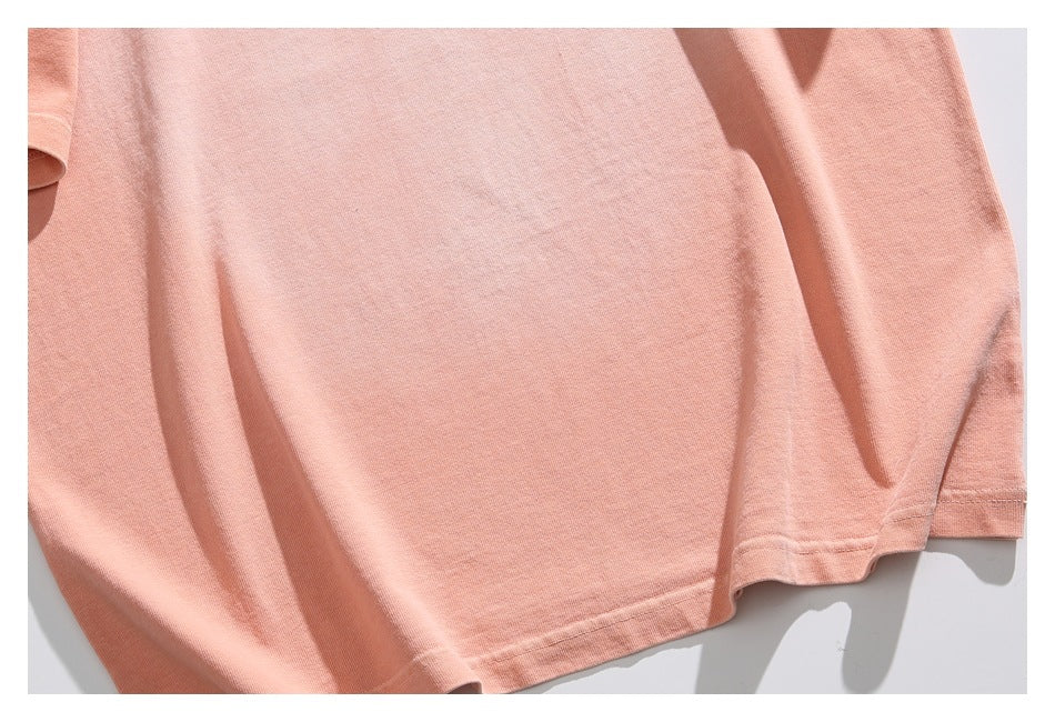 Close-up of the peach T-shirt body and stitched bottom hem.