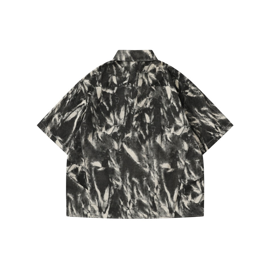 Back view of a short-sleeve button-up shirt in a black and cream abstract pattern.
