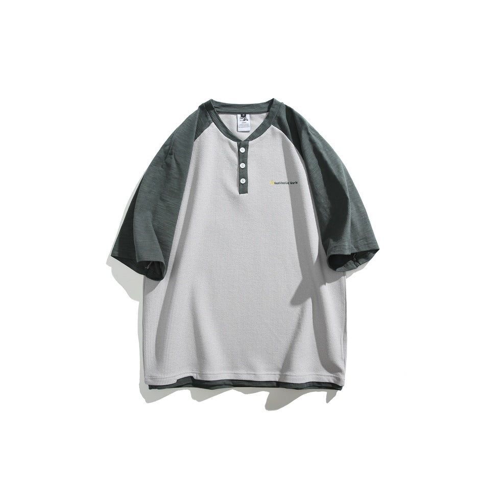 Light gray waffle-texture Henley T-shirt with dark green raglan sleeves, three buttons and small chest print, flat lay