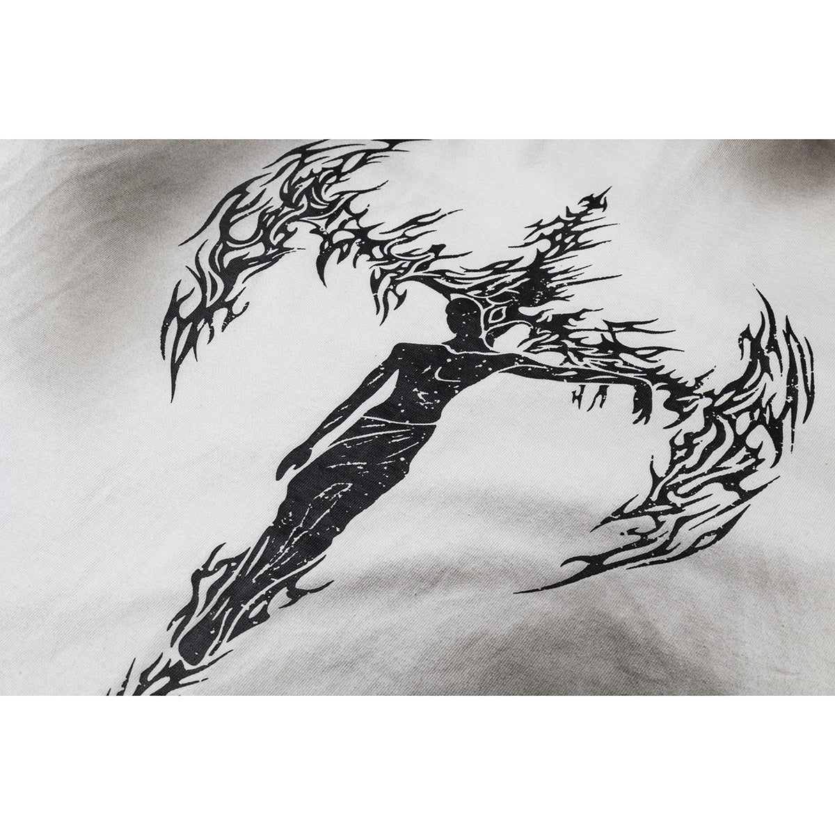 Close-up of a black flame-like graphic with a figure printed on white T-shirt fabric.