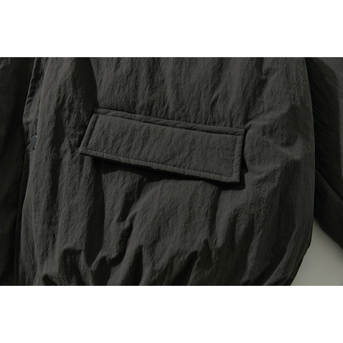 Close-up of a rectangular flap pocket on the dark jacket.