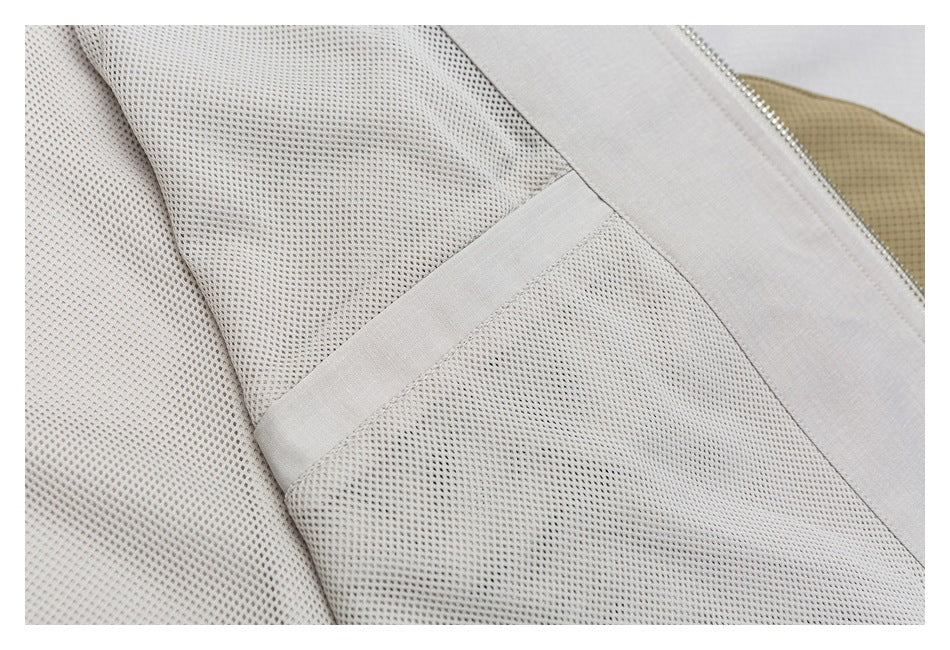 Close-up of pale mesh lining with gray trim and a glimpse of tan fabric.