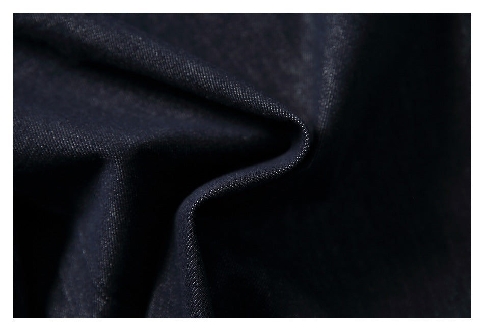 Macro view of dark indigo denim draped to show its woven surface and texture.