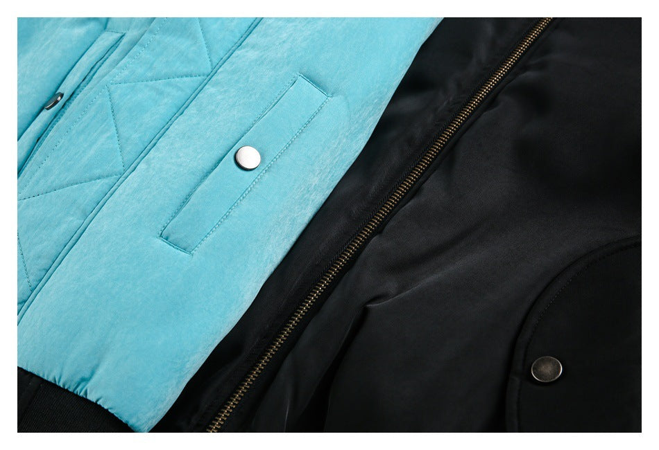 Close-up of turquoise and black jacket panels, showing stitching, a snap pocket, and the zipper.