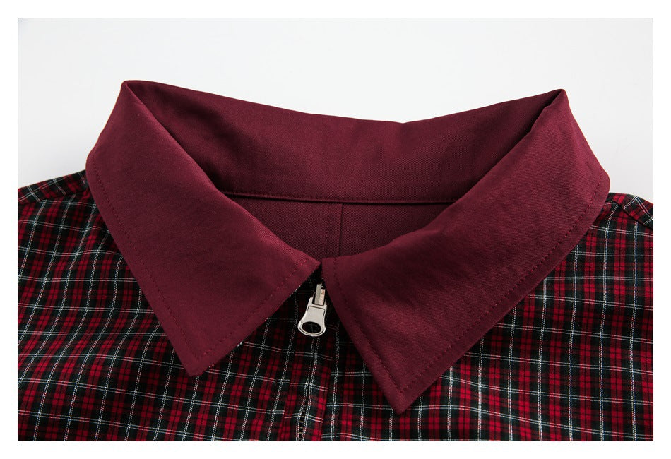 Close-up of a pointed burgundy collar, zipper, and red, black, and white plaid jacket body.