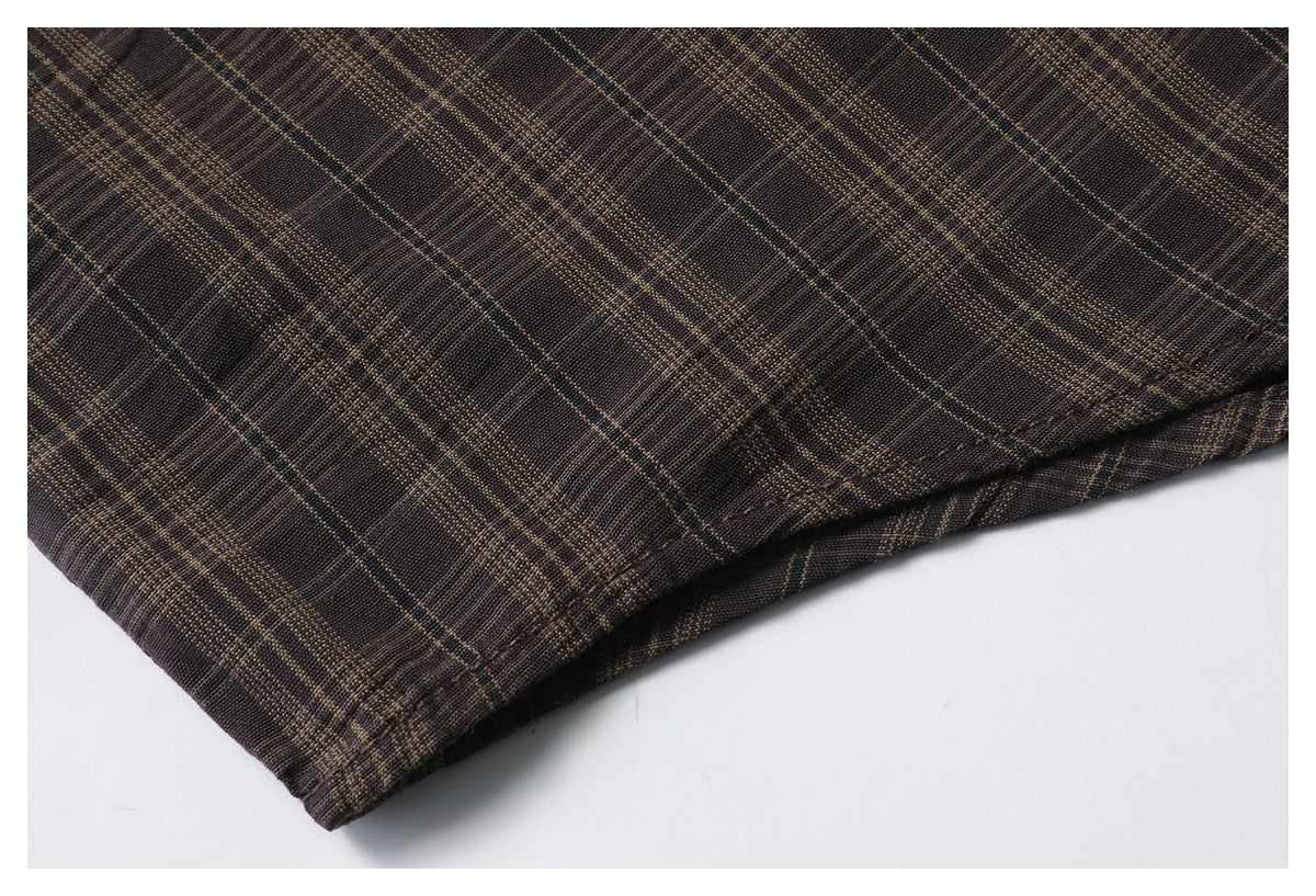 Close-up of dark brown plaid fabric with tan windowpane lines and a stitched folded hem.