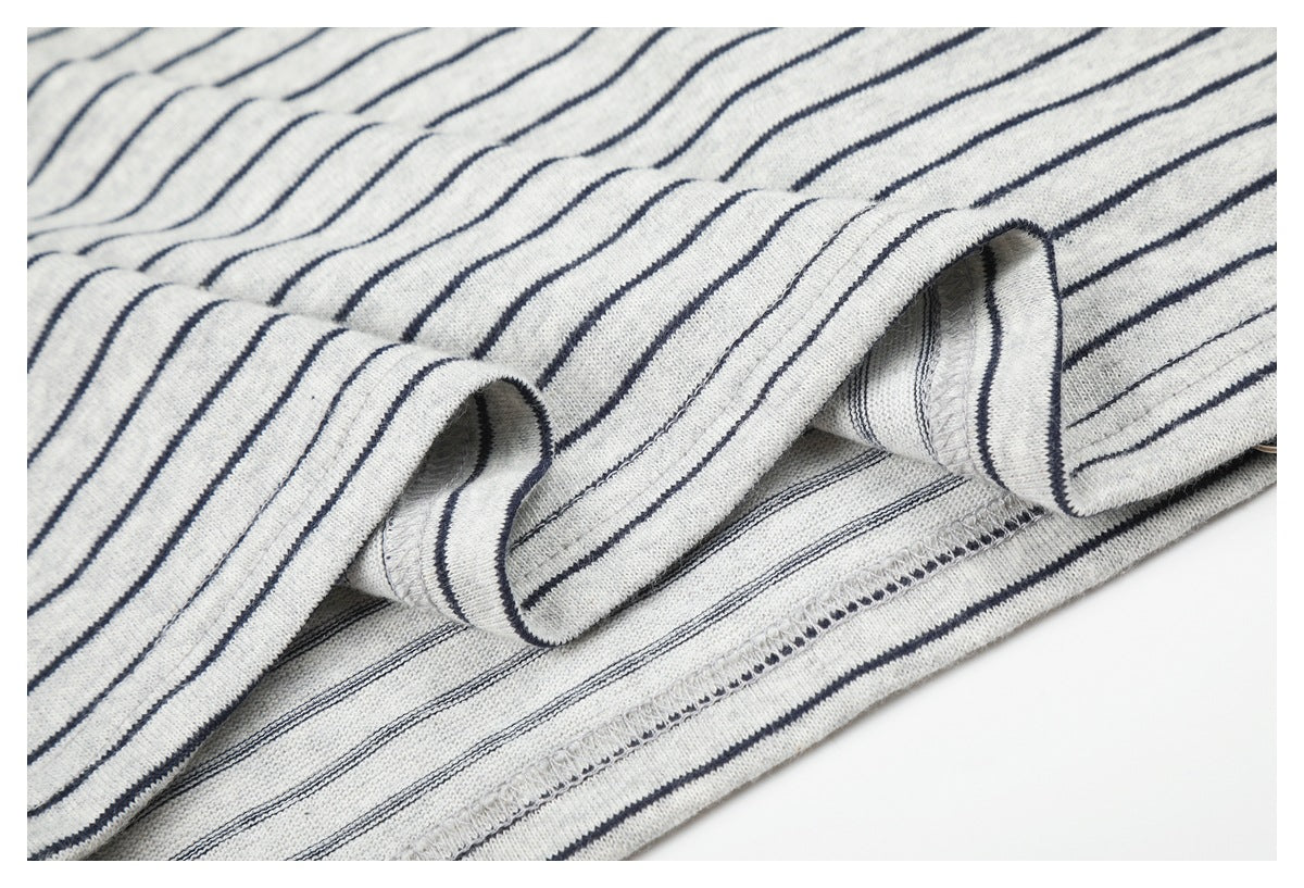 Close-up of a folded hem on light gray fabric with navy stripes, showing the overlocked seam.