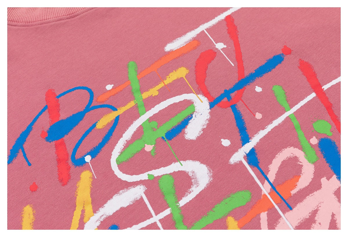 Tight view of the sweatshirt's multicolored abstract brushstroke print on dusty rose fabric.