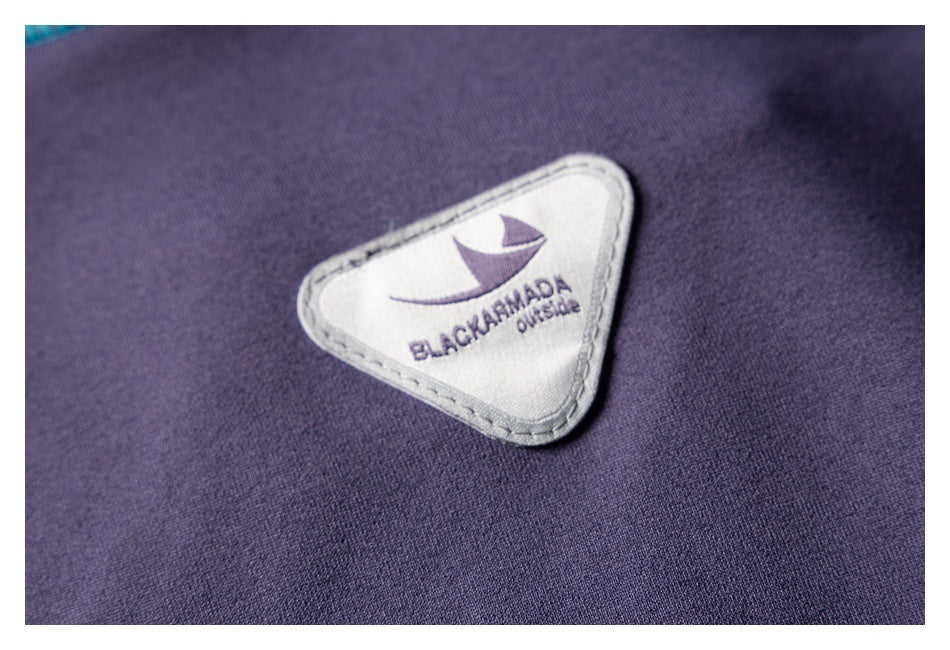 Close-up of a triangular BLACK ARMADA OUTSIDE brand patch sewn onto dark purple fabric.