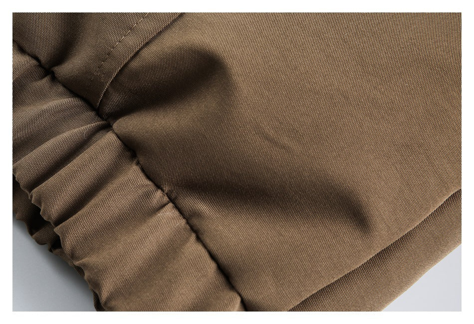 Close-up of brown fabric with a stitched seam beside a gathered elastic edge.