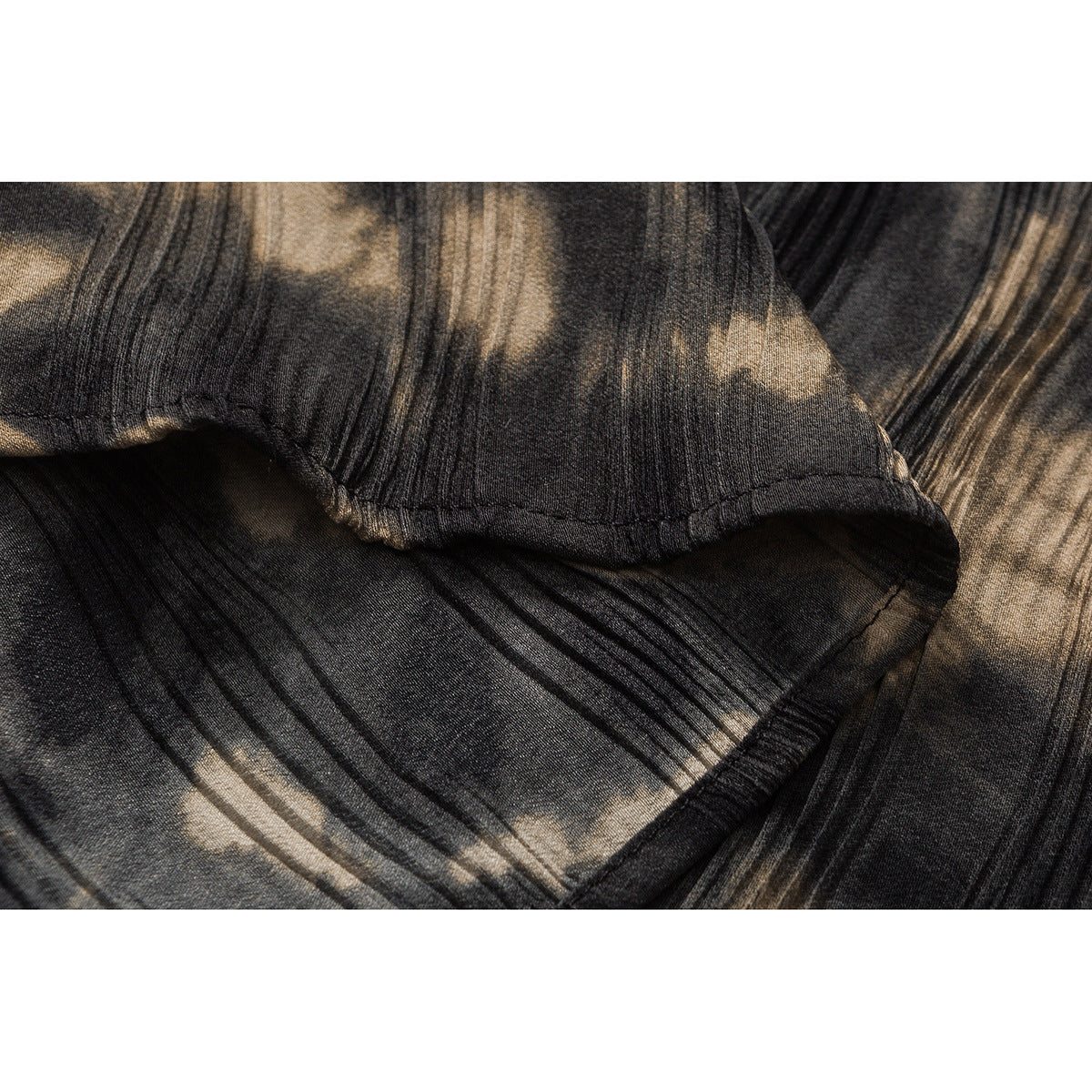 Close-up of the stitched hem and textured black and tan pattern on a shirt.