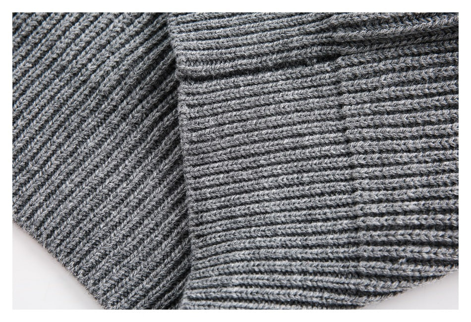 Close-up of the gray sweater's ribbed knit construction and seam.