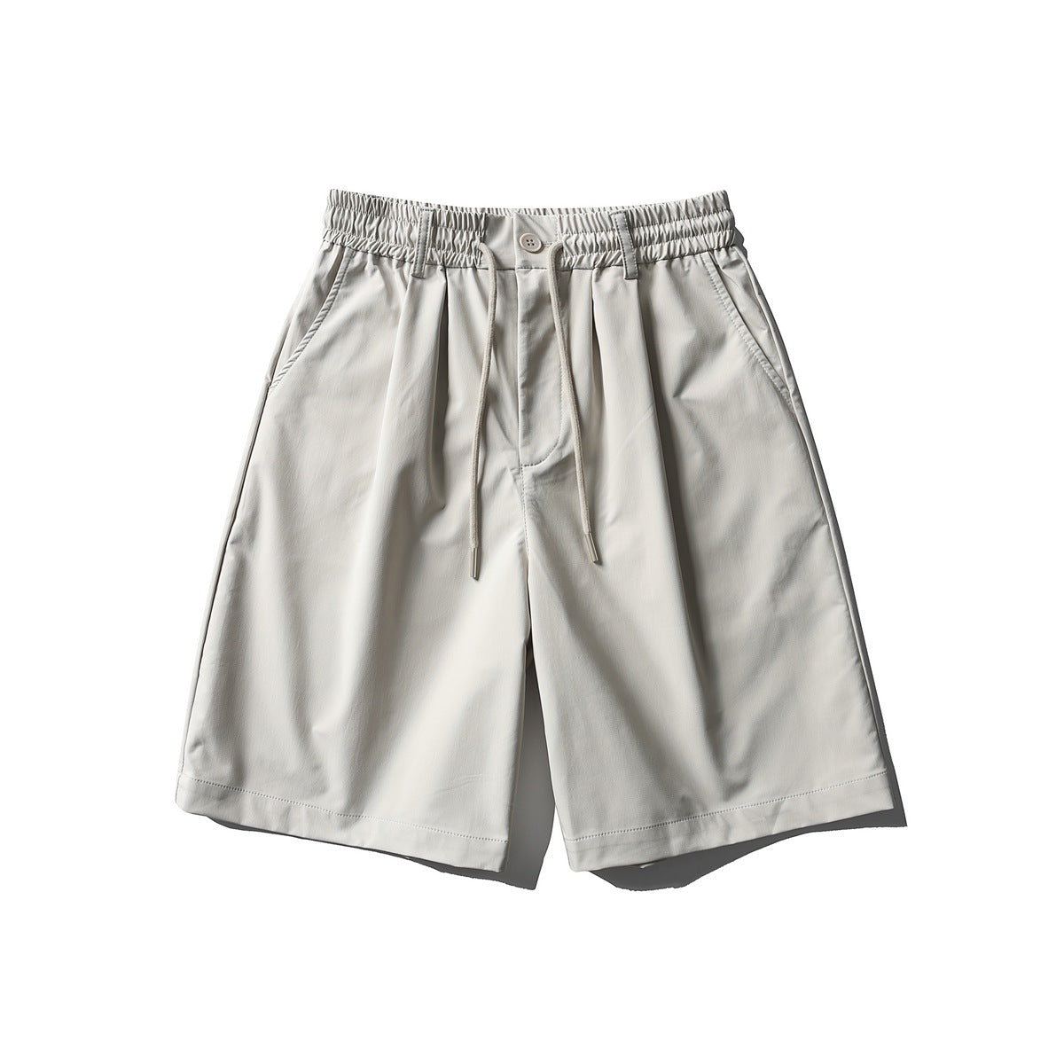 Off-white knee-length shorts with elastic drawstring waist, button front, pleats and side pockets, flat lay front view