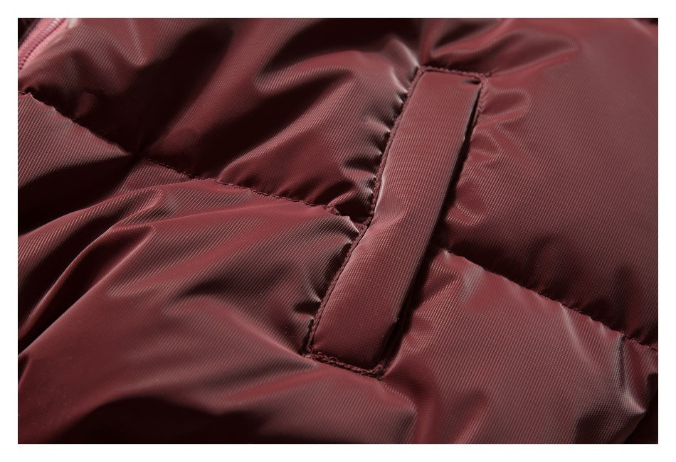 Close-up of burgundy quilted jacket construction and a narrow fabric strip sewn across a panel.