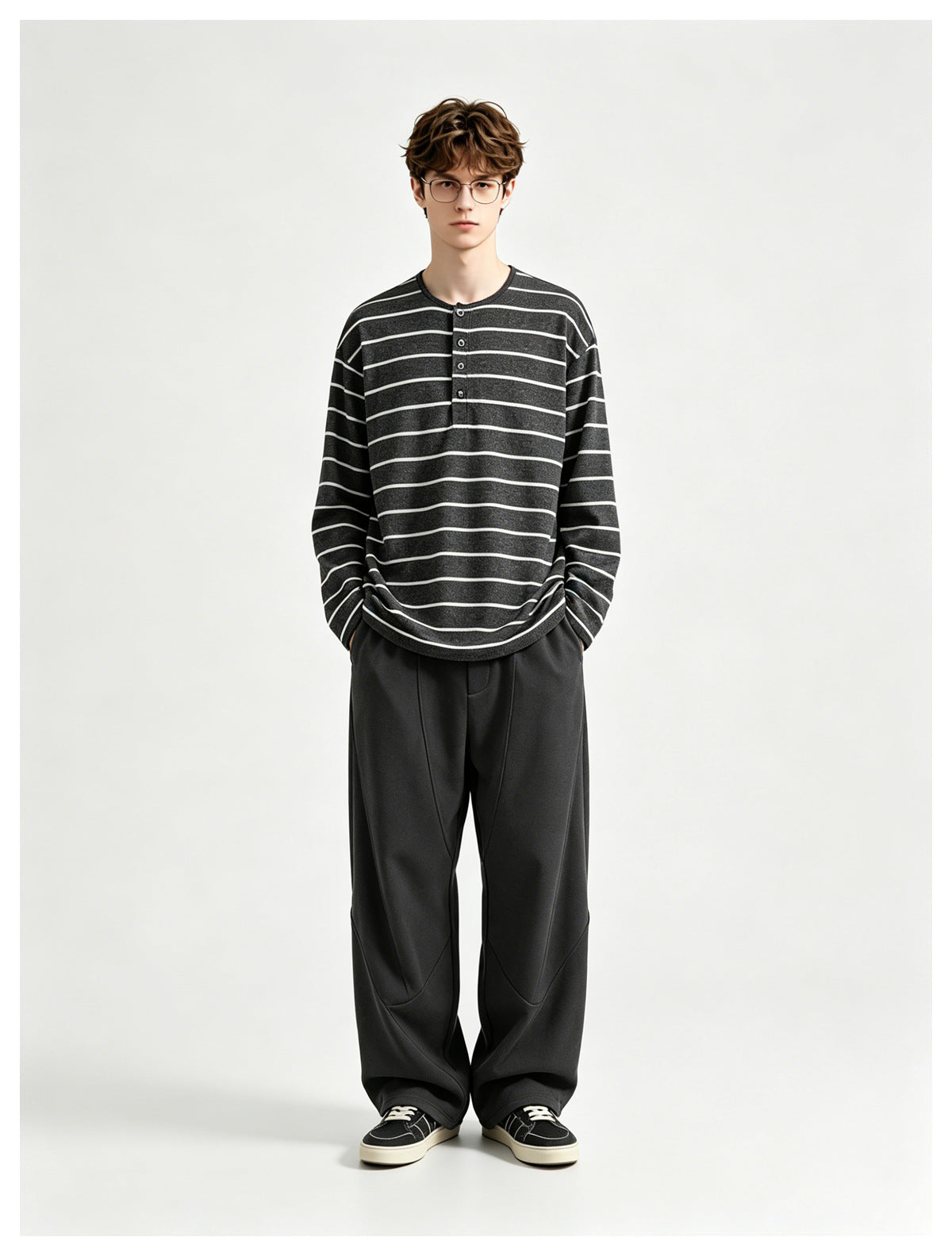 Model wearing a charcoal long-sleeve Henley with thin light horizontal stripes and loose black trousers.