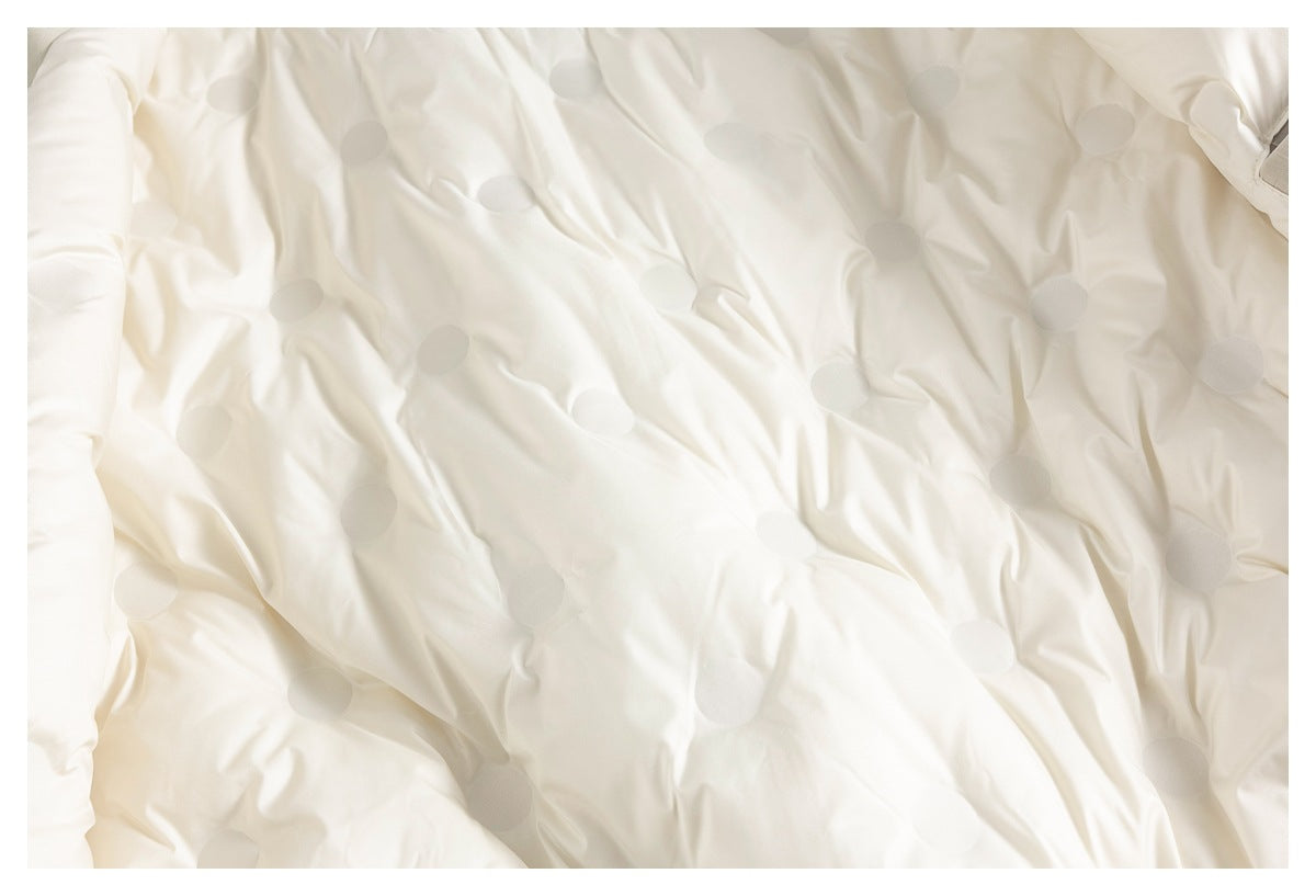 Close-up of cream jacket fabric with scattered subtle circular details and soft folds.