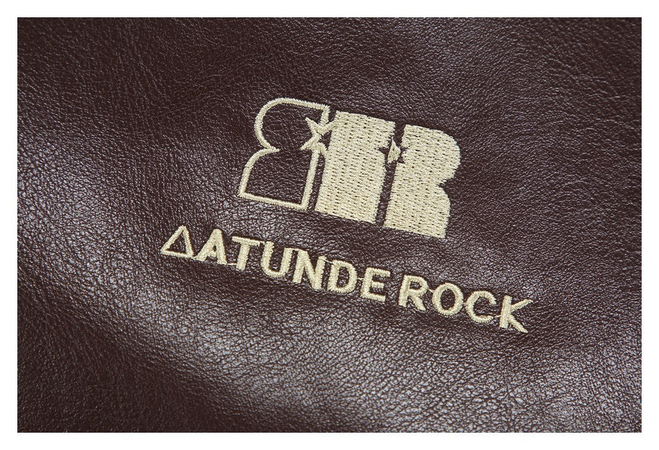 Cream-colored embroidered emblem and lettering on the dark brown jacket surface.