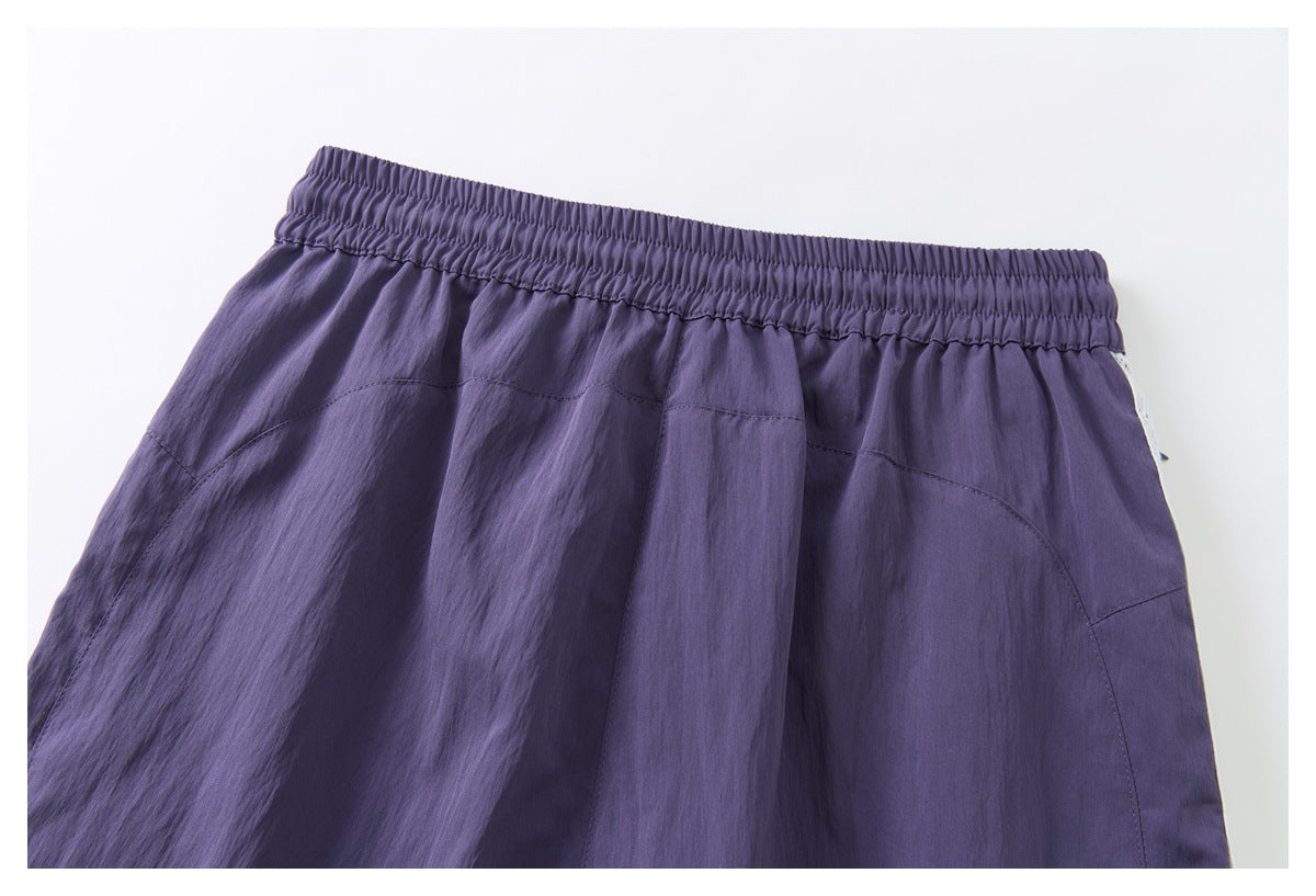 Close-up of the back waistband and upper panels of purple pants laid flat.