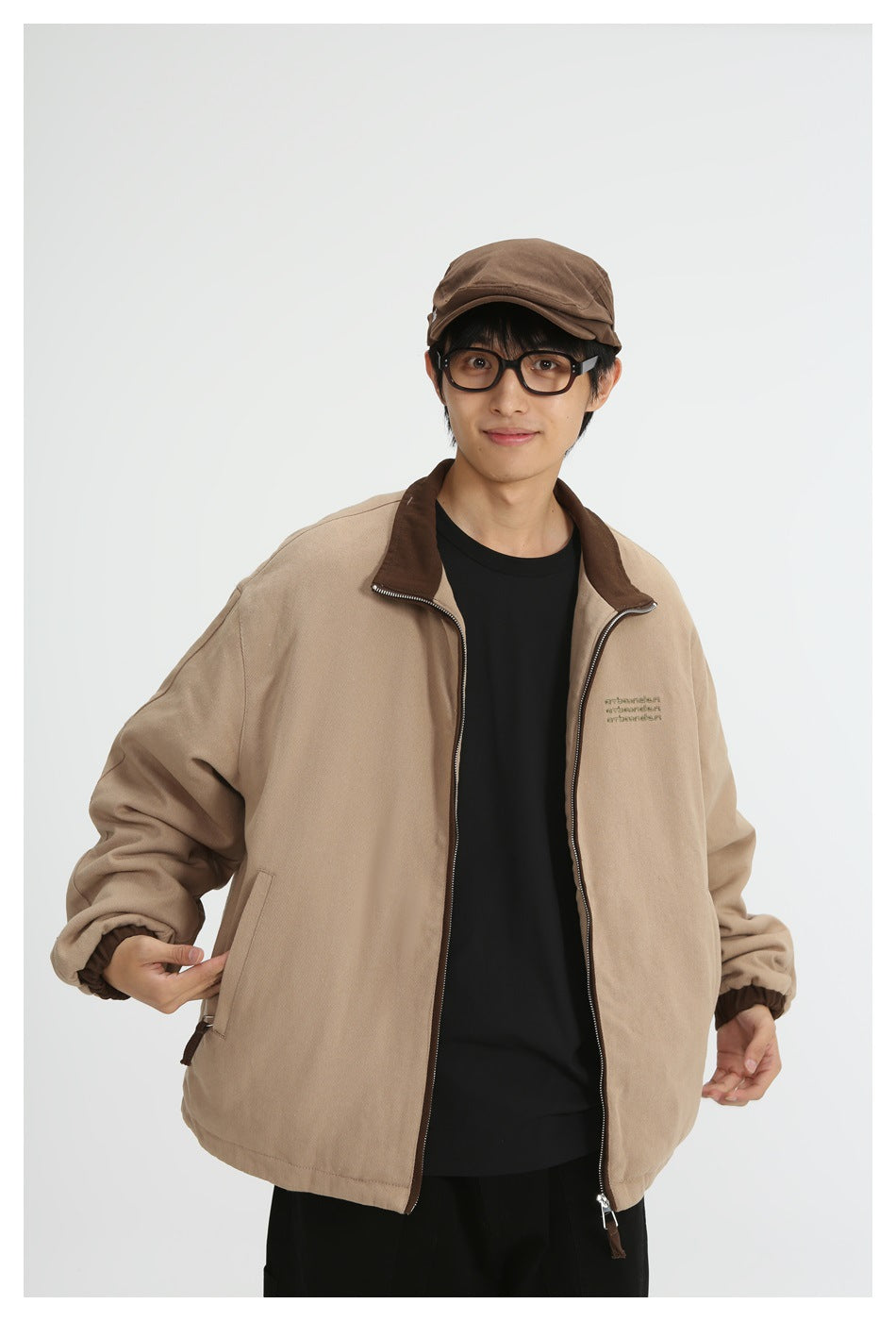 Front view of a model wearing a tan zip jacket with a dark brown collar over a black shirt.